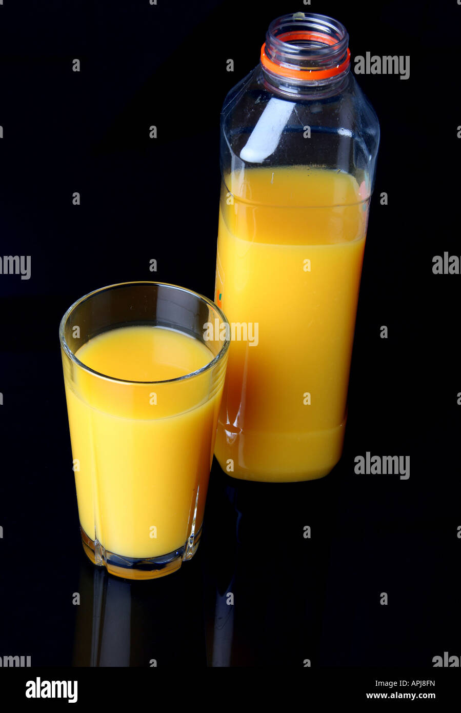 Full glass of orange juice and orange juice bottle standing next to it