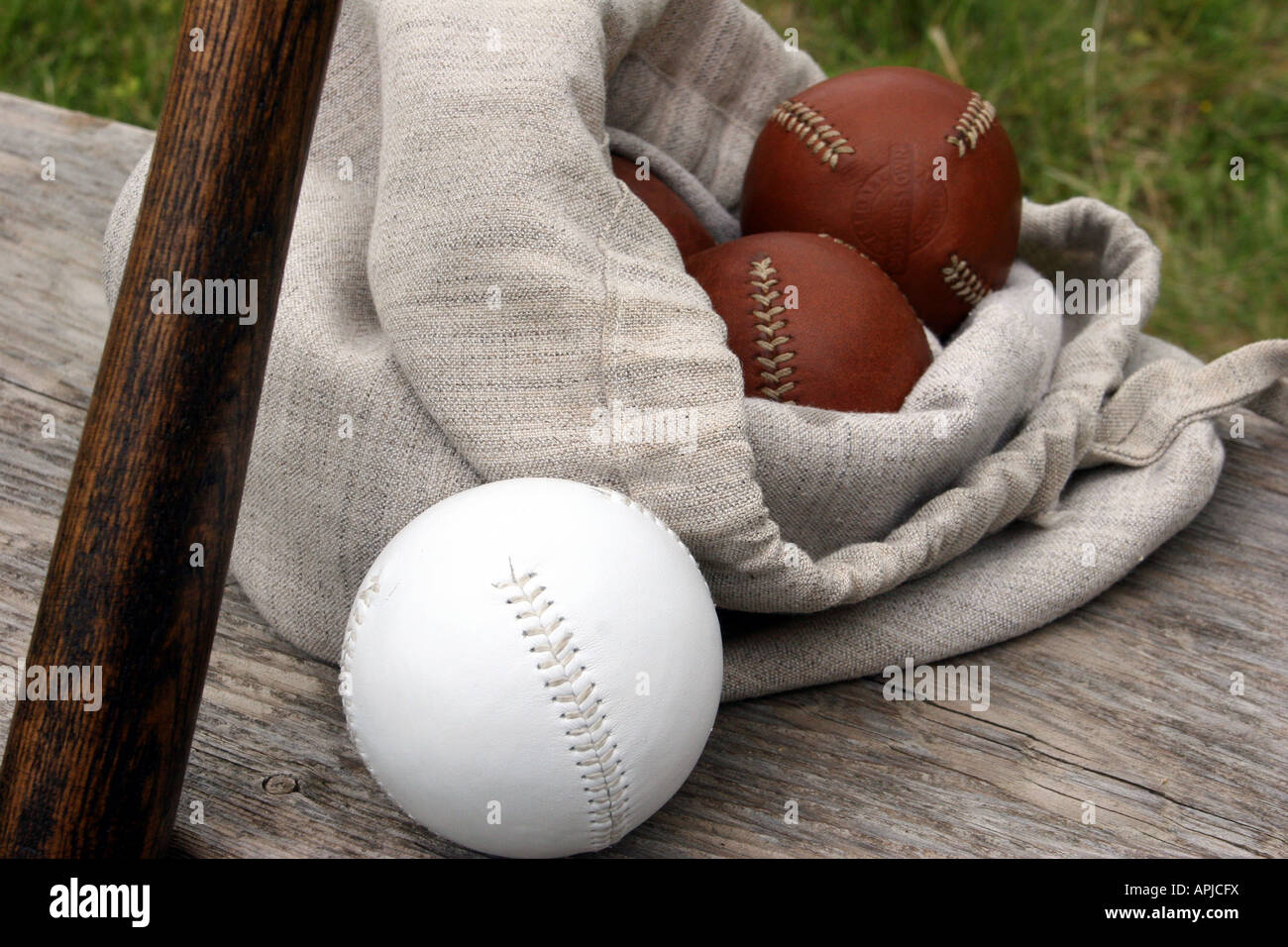 Leather handsewn vintage baseballs by the Cooperstown Baseball Company in a burlap bag and a soft ball and bat at a reenactment Stock Photo