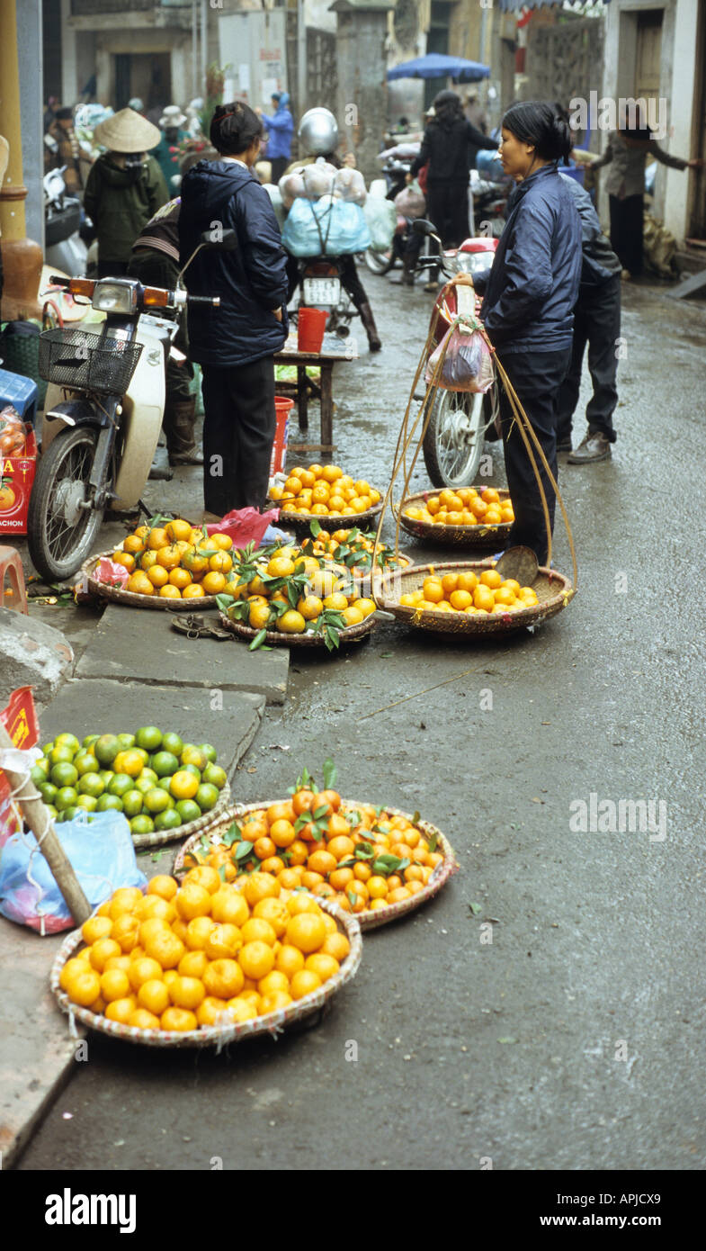 Street vendors selling fruit from baskets on the roadside in Thanh Ha St, Hanoi Old Quarter, Viet Nam Stock Photo