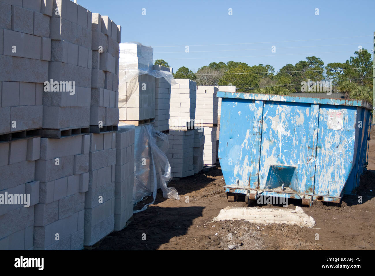 White brick construction material and a dumpster. Stock Photo