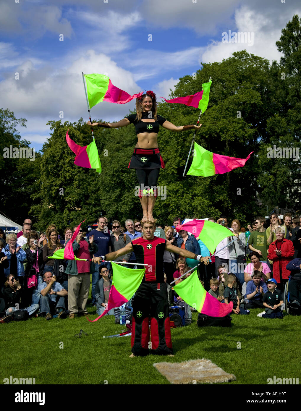 Female balancing on males head while twirling flags, Edinburgh Fringe Sunday Festival, Scotland, UK, Europe Stock Photo