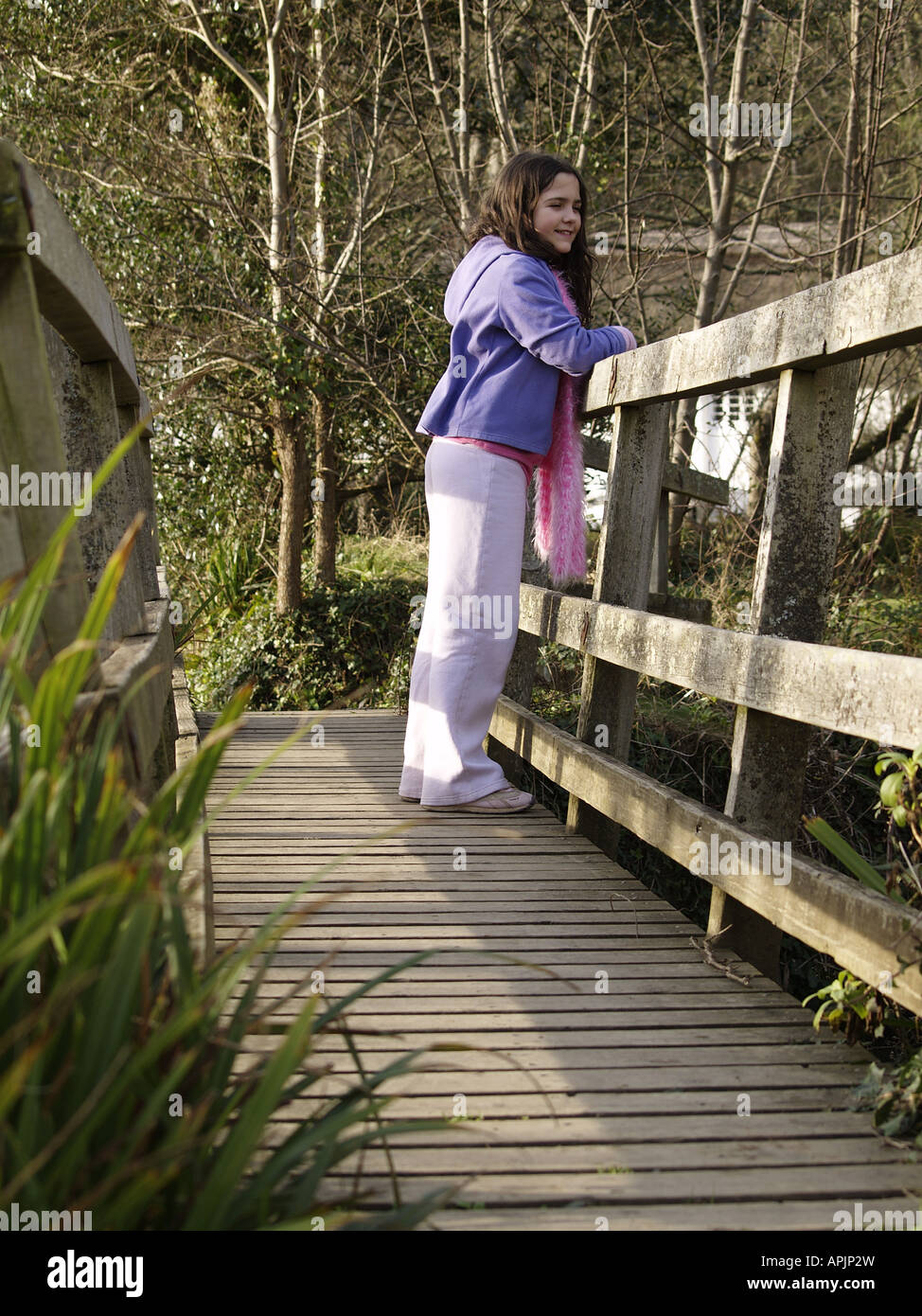 Young girl on wooden foot bridge laughing Stock Photo