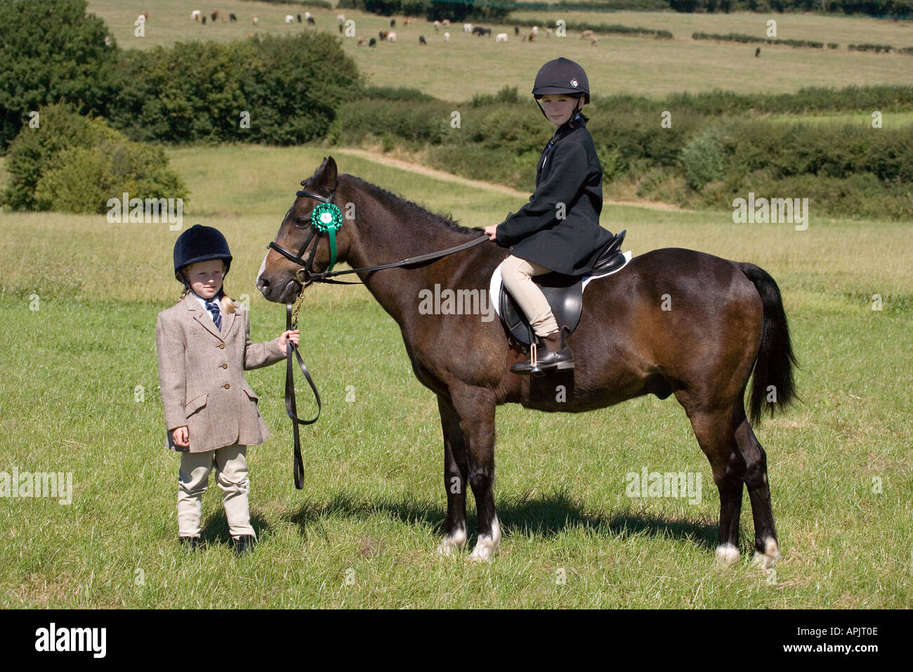TWO LITTLE GIRLS IN RIDING OUTFITS WITH PONY IN FIELD UK Stock Photo