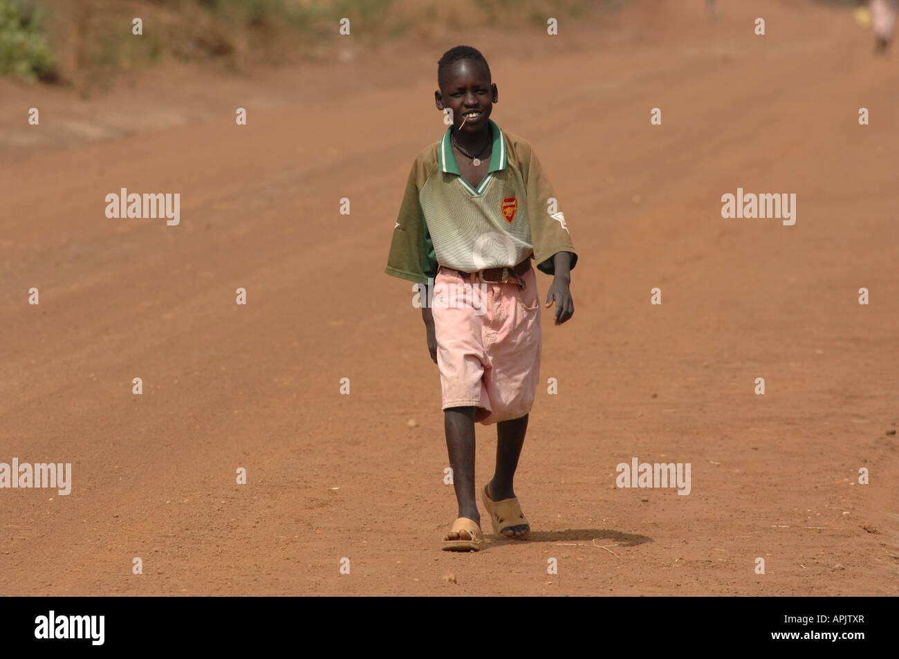 African child in Manchester United kit on a dirt road in Sudan Stock Photo