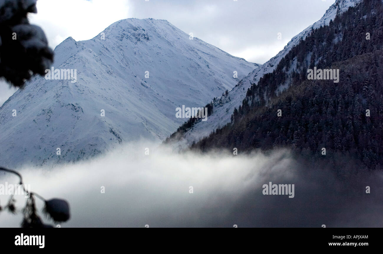 Mist rising in the valley of Saas Fee in Wallis mountain range in Switzerland Stock Photo