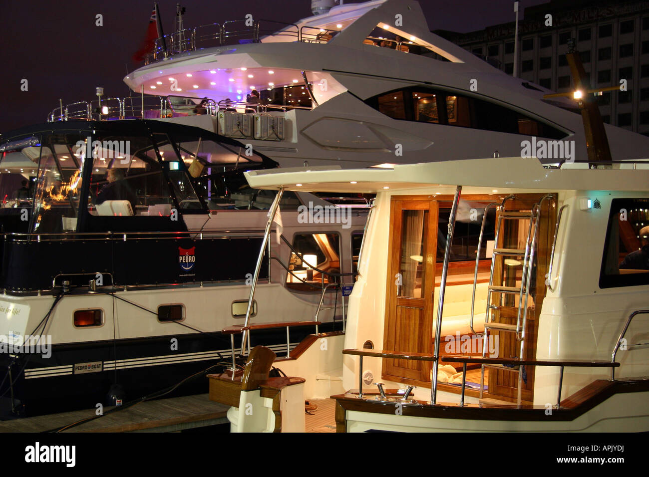 Luxury boats moored on the marina in the evening with the lights on. Stock Photo