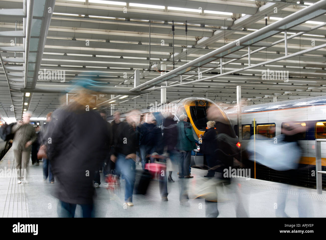 Passengers pour off an East Midlands Trains Class 222 meridian at St Pancras but it is yet to be repainted It is still in Midland Mainline livery. Movement blur prevents individual identity and maintains the idea of people wanting to get to their destination quickly. St. Pancras Station, London, UK. Stock Photo