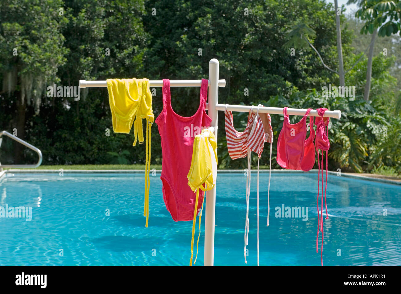 several female swim suits drying outdoors on rack by pool Stock Photo