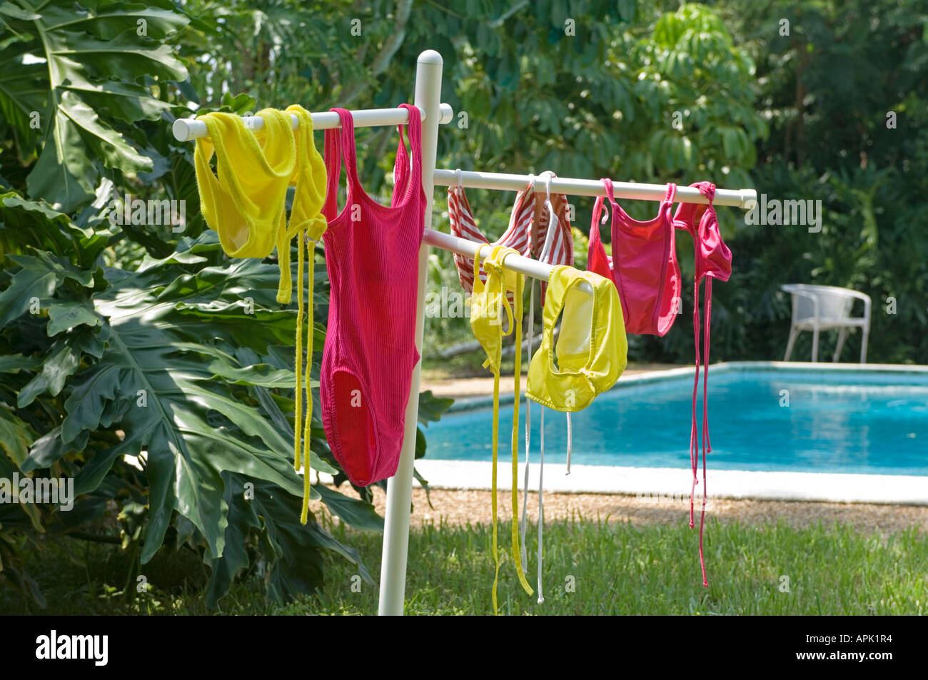 several female swim suits drying outdoors on rack by pool Stock Photo