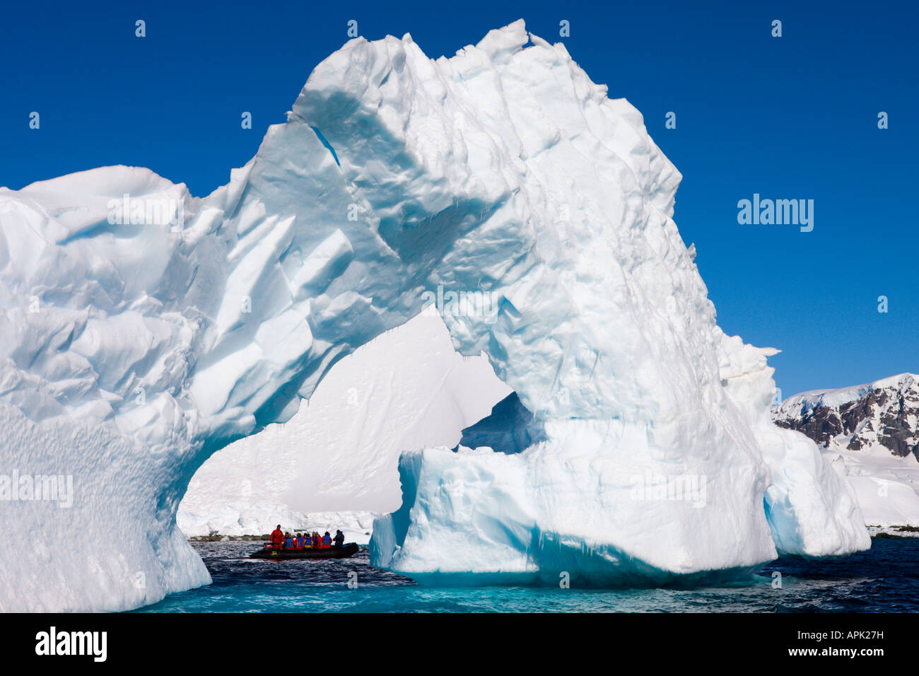 Magnificent arched iceberg with tourist Zodiac boat underneath, Antarctica Stock Photo