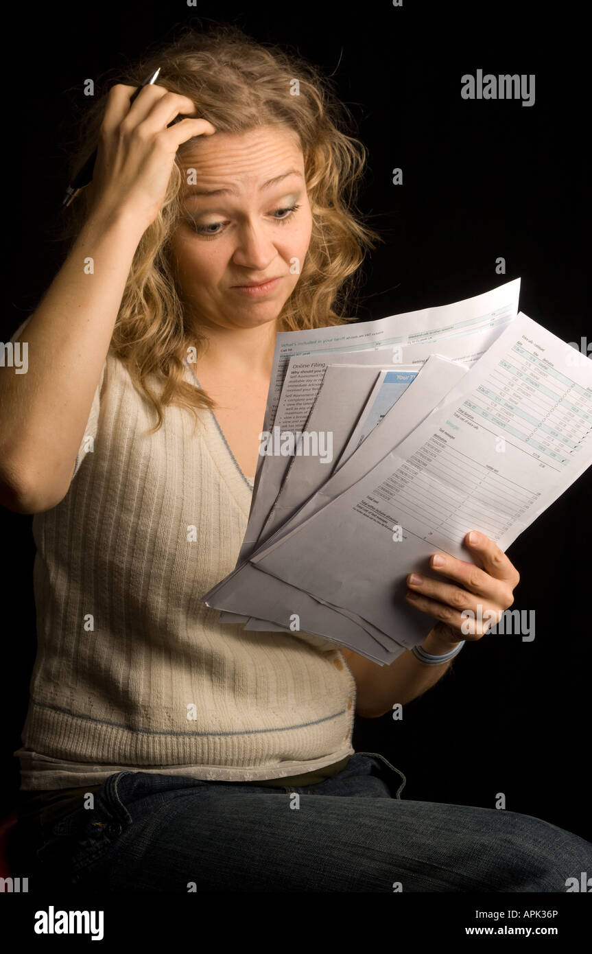 woman holding household bills looking worried and concerned at her ability to pay for gas electricity and telephone costs UK Stock Photo