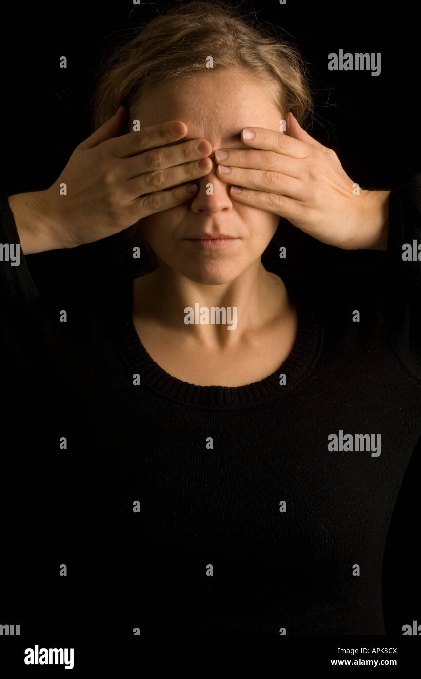 blonde woman in studio with hands over her eyes seeing no evil ...