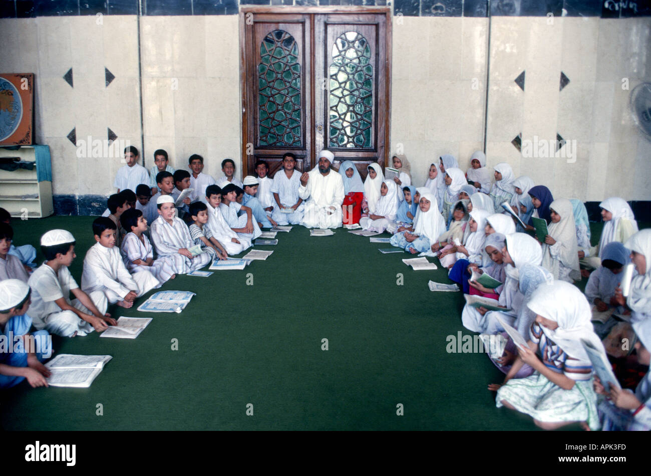 IRAQ BAGHDAD Imam al-A'dham Mosque Islamic school boys and girls in traditional dress study the Koran with their Imam Stock Photo
