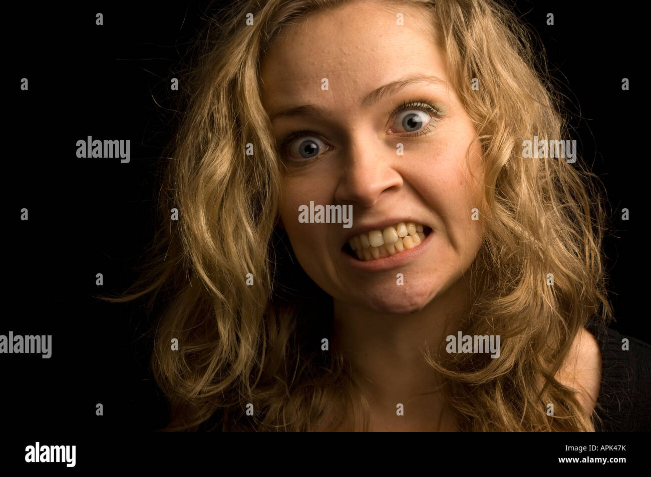 young blonde haired woman staring and snarling at the camera in anger and frustration Stock Photo
