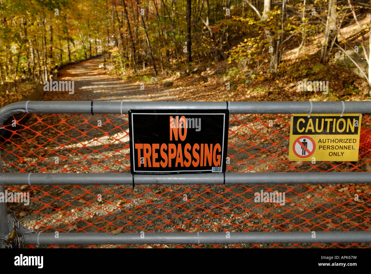 No trespassing sign and closed gate before a woods country road leading to a toxic waste clean up site Stock Photo