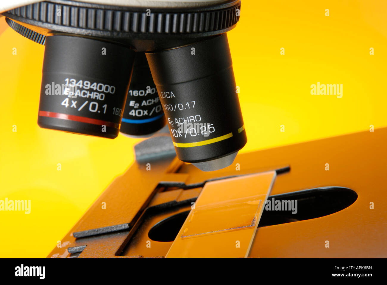 Close up of a microscope in a research lab showing the objective lenses and a slide Stock Photo