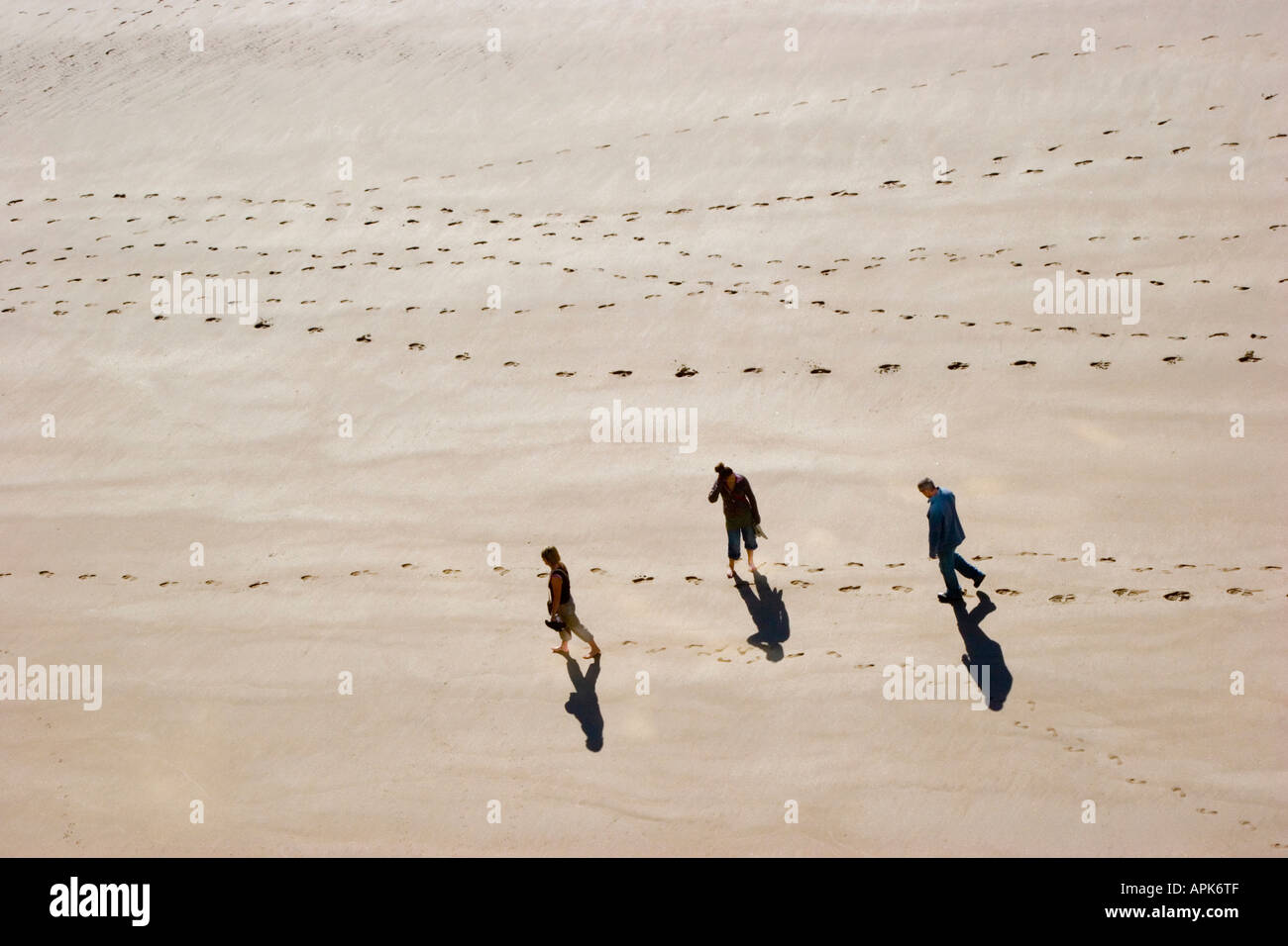 Footprints in the sand and three people walking on the beach Stock ...