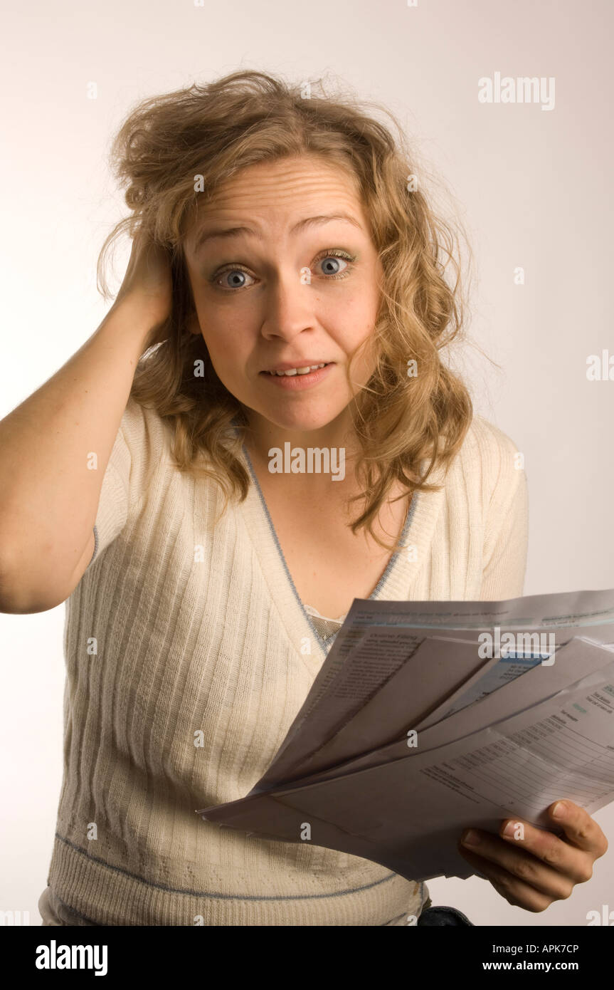 woman holding household bills looking worried and concerned at her ability to pay for gas electricity and telephone costs UK Stock Photo