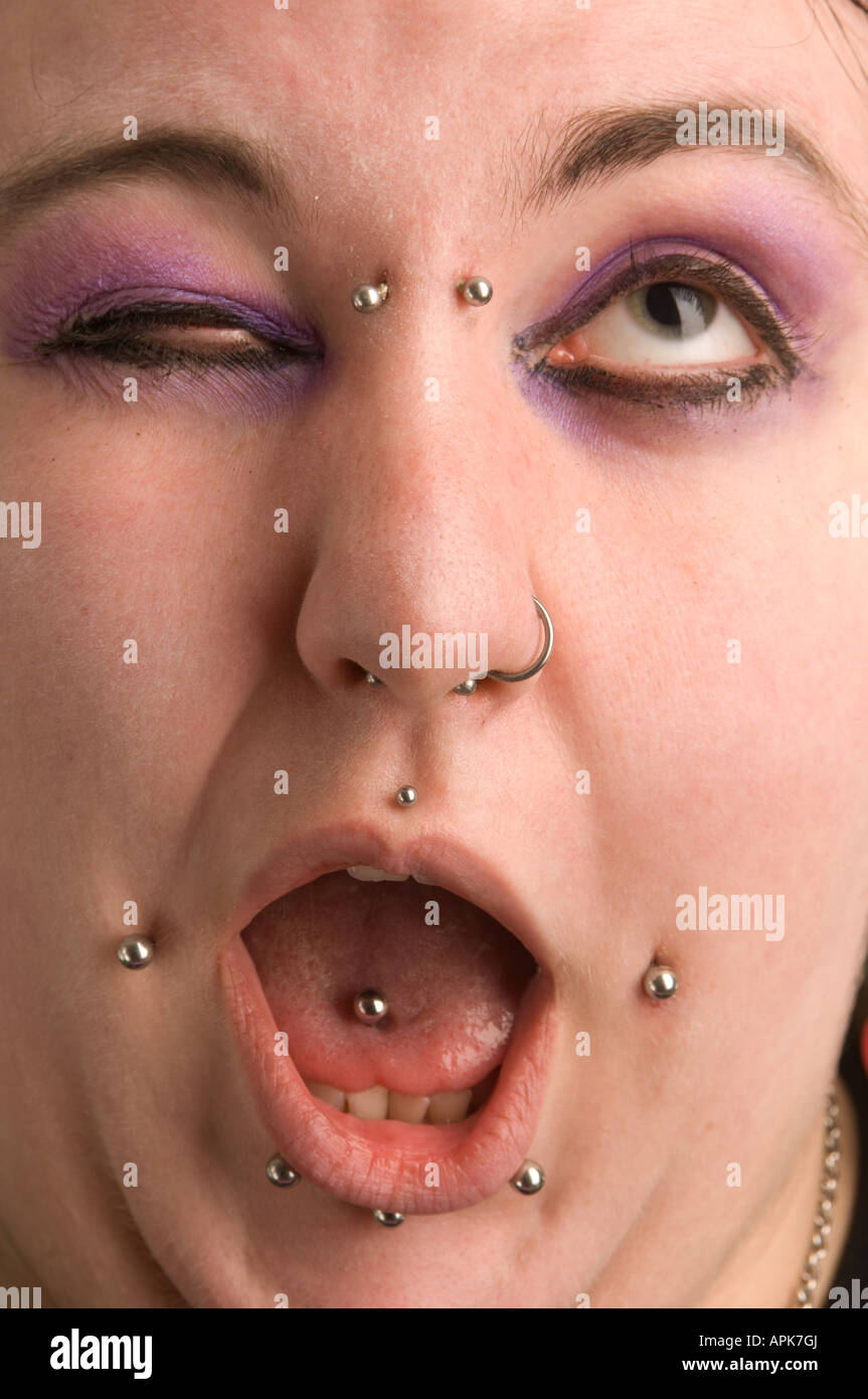 young punk goth welsh woman; she has multiple facial piercings UK  winking at camera mouth open pierced tongue Stock Photo
