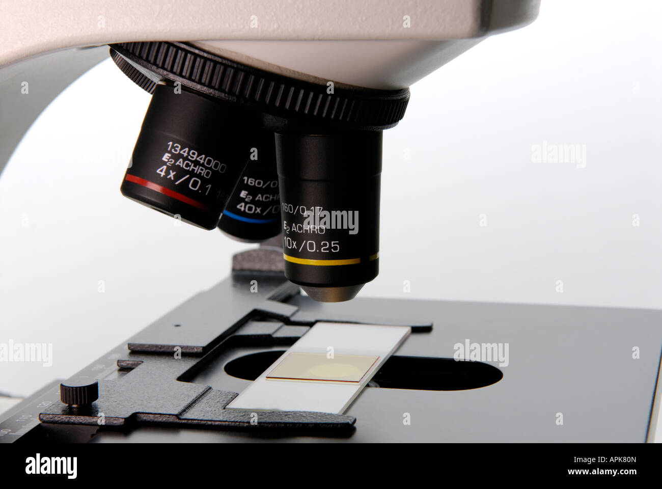 Close up of a microscope in a research lab showing the objective lenses and a slide Stock Photo