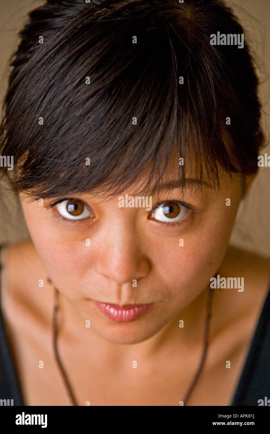 Close-up portrait beautiful asian oriental Chinese young woman big brown eyes smiling looking up at camera Beijing China JMH2989 Stock Photo
