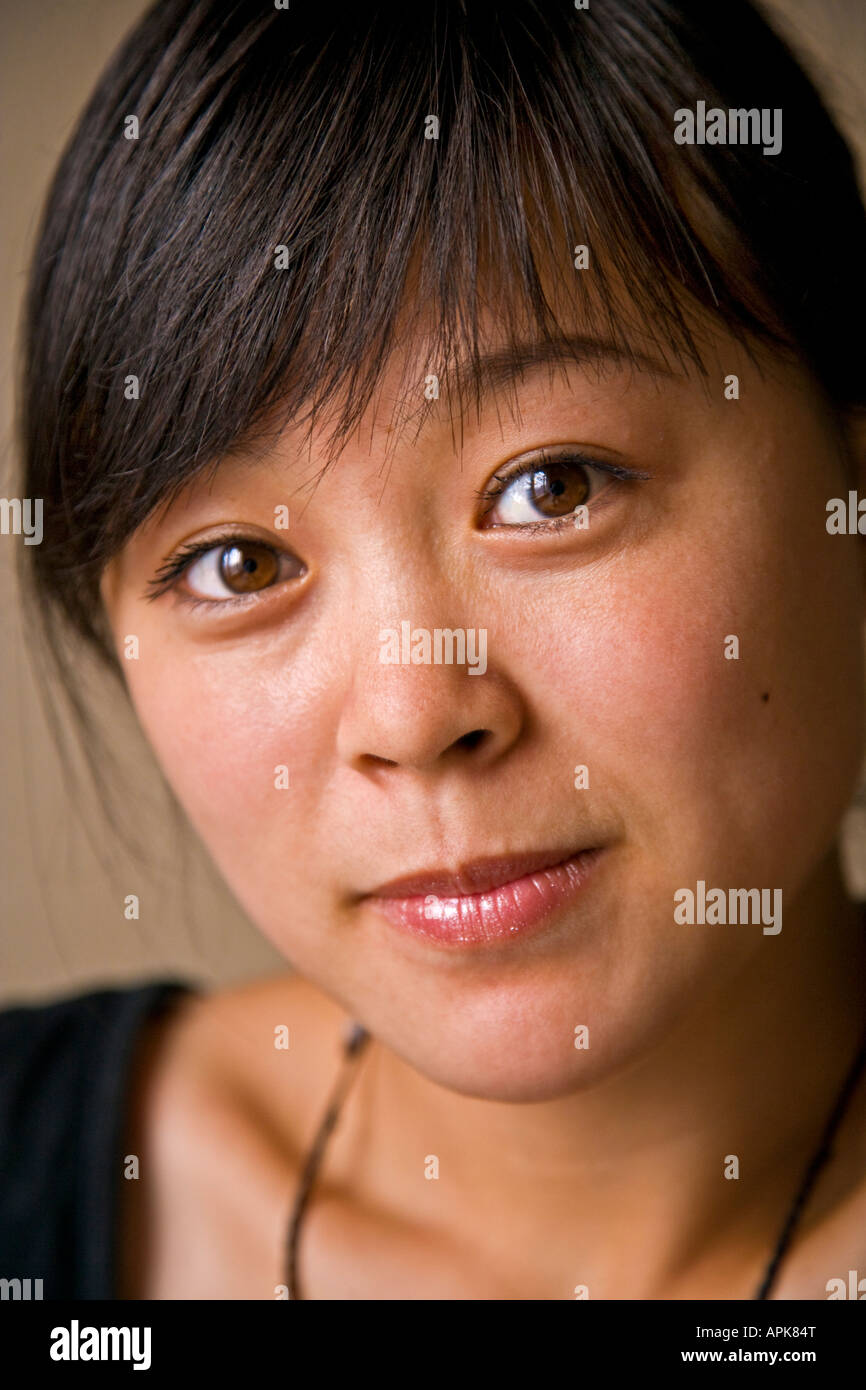 Close-up portrait beautiful asian oriental Chinese young woman big brown eyes smiling looking at camera Beijing China JMH2992 Stock Photo