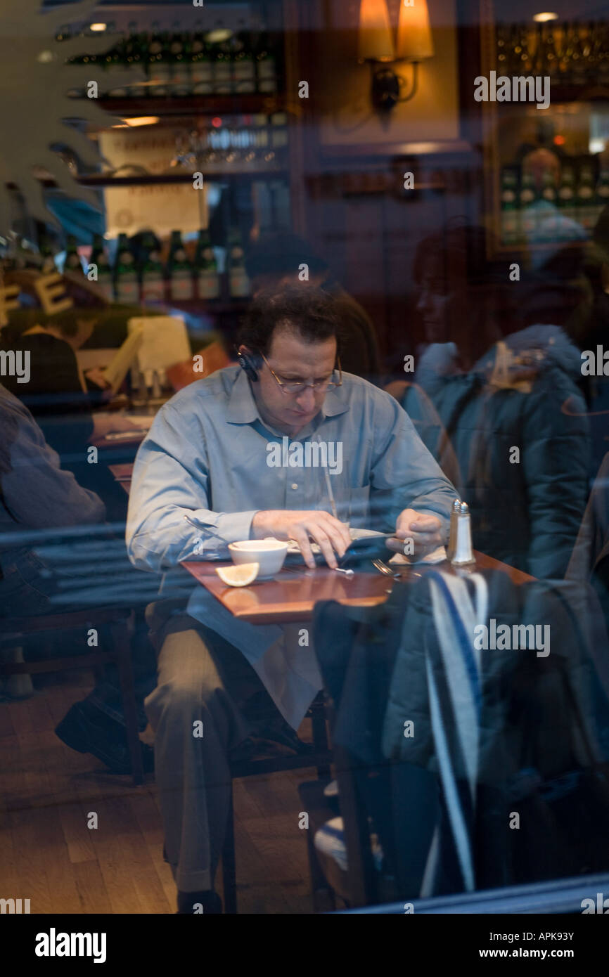 Man immersed in personal technology over lunch at a cafe in Manhattan Stock Photo