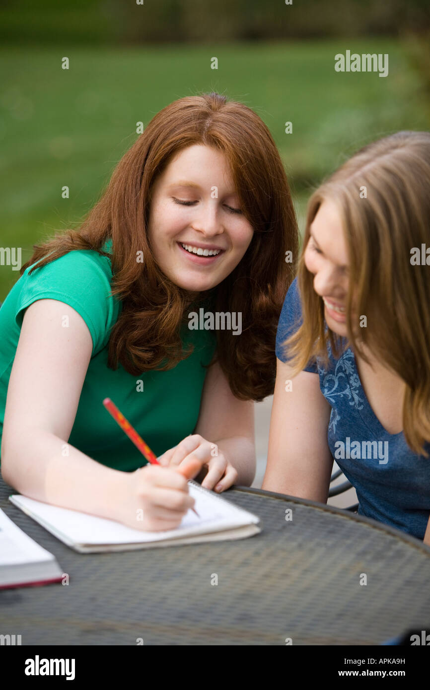 ILLINOIS Riverwoods Two teenage girls goofing around together redhead writing in notebook and laughing sitting at table Stock Photo