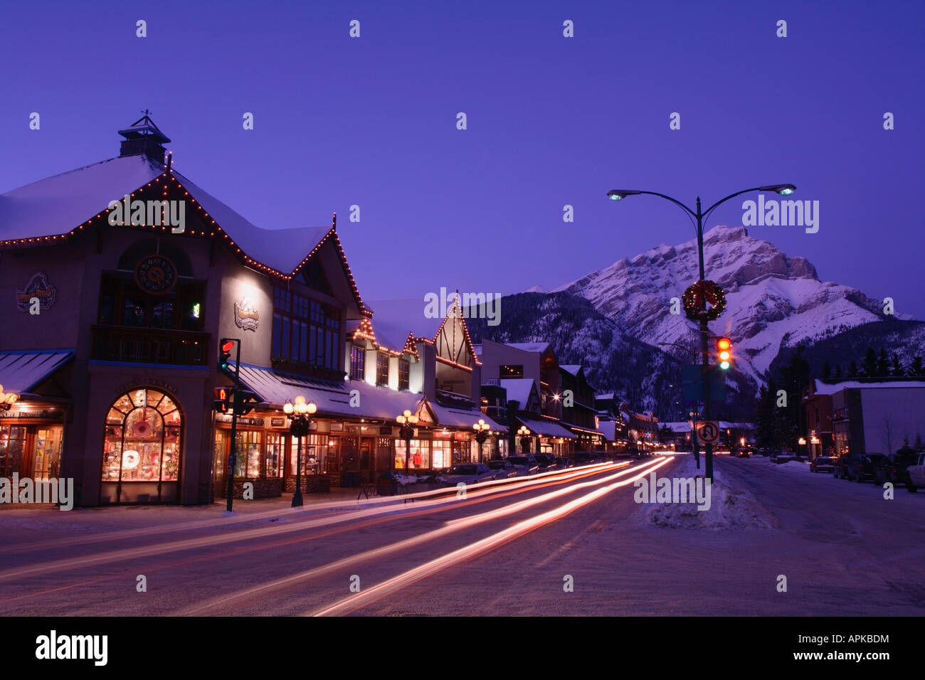 Shops along Banff Avenue at night dusk in winter with Cascade Mountain in the background Banff Alberta Canada Stock Photo