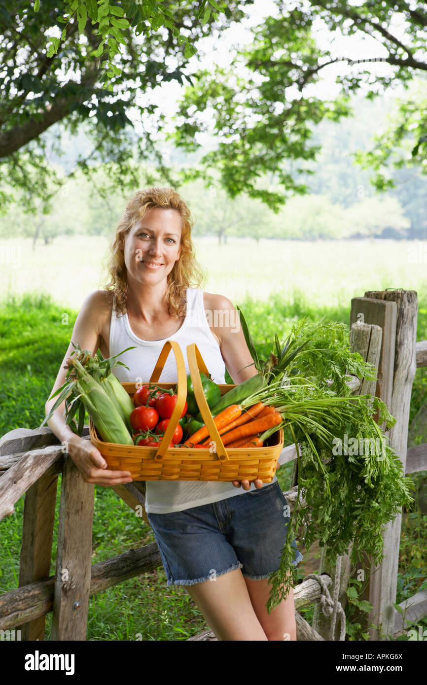 Woman holding fresh vegetable basket (portrait) Stock Photo