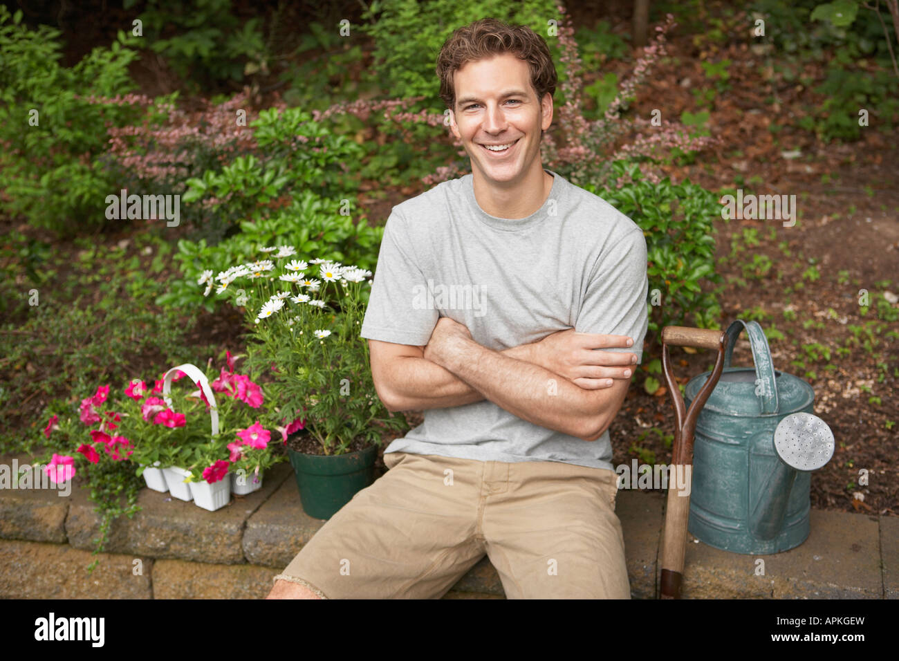 Gardener sitting by flowers and watering can (portrait) Stock Photo