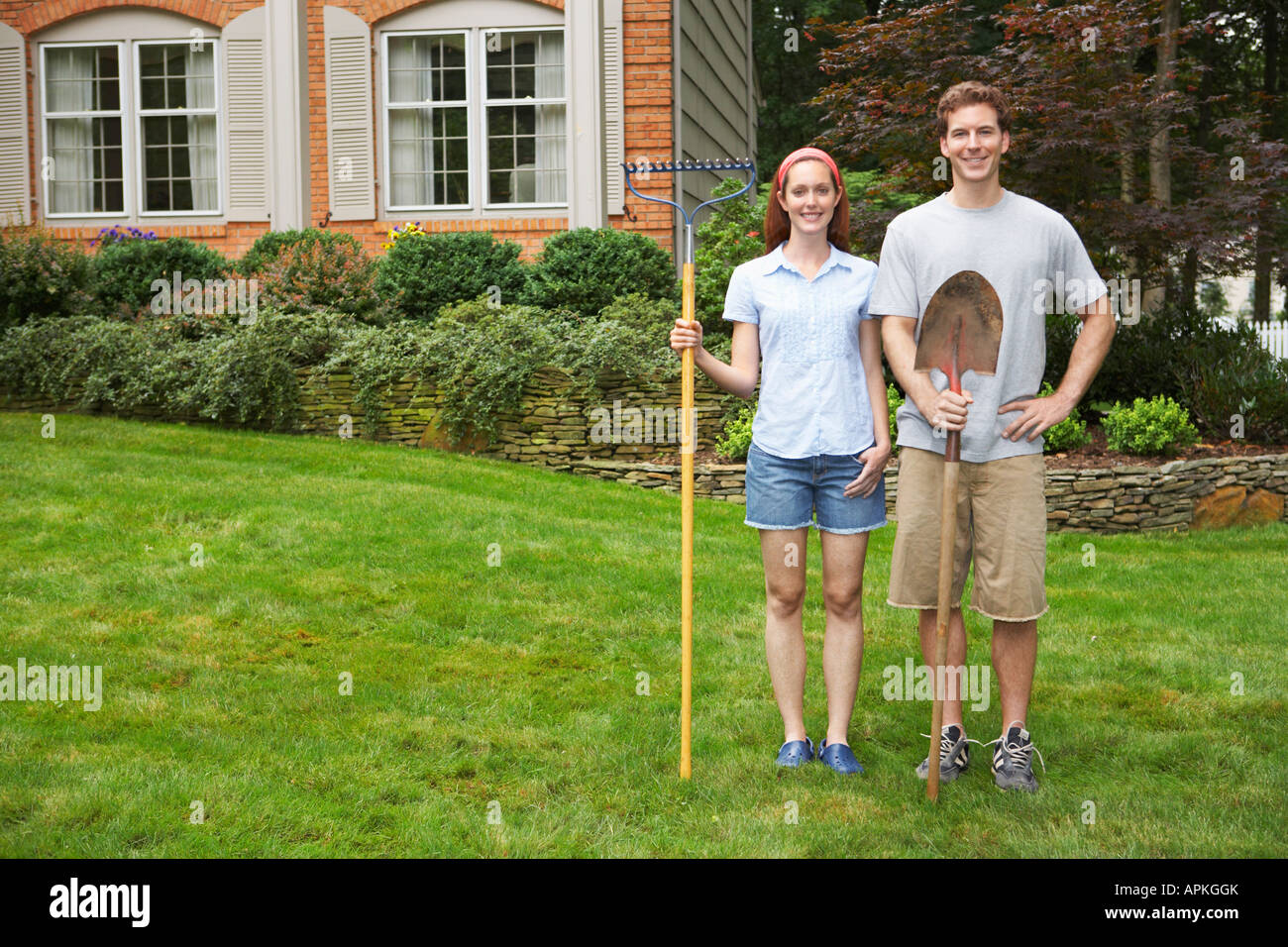 Young couple with rake and spade in garden Stock Photo