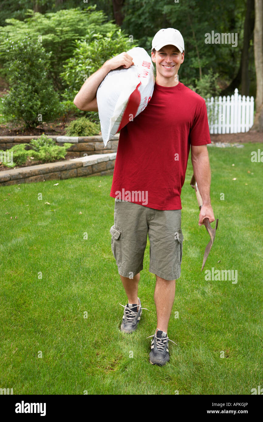 Young man carrying sack in garden Stock Photo