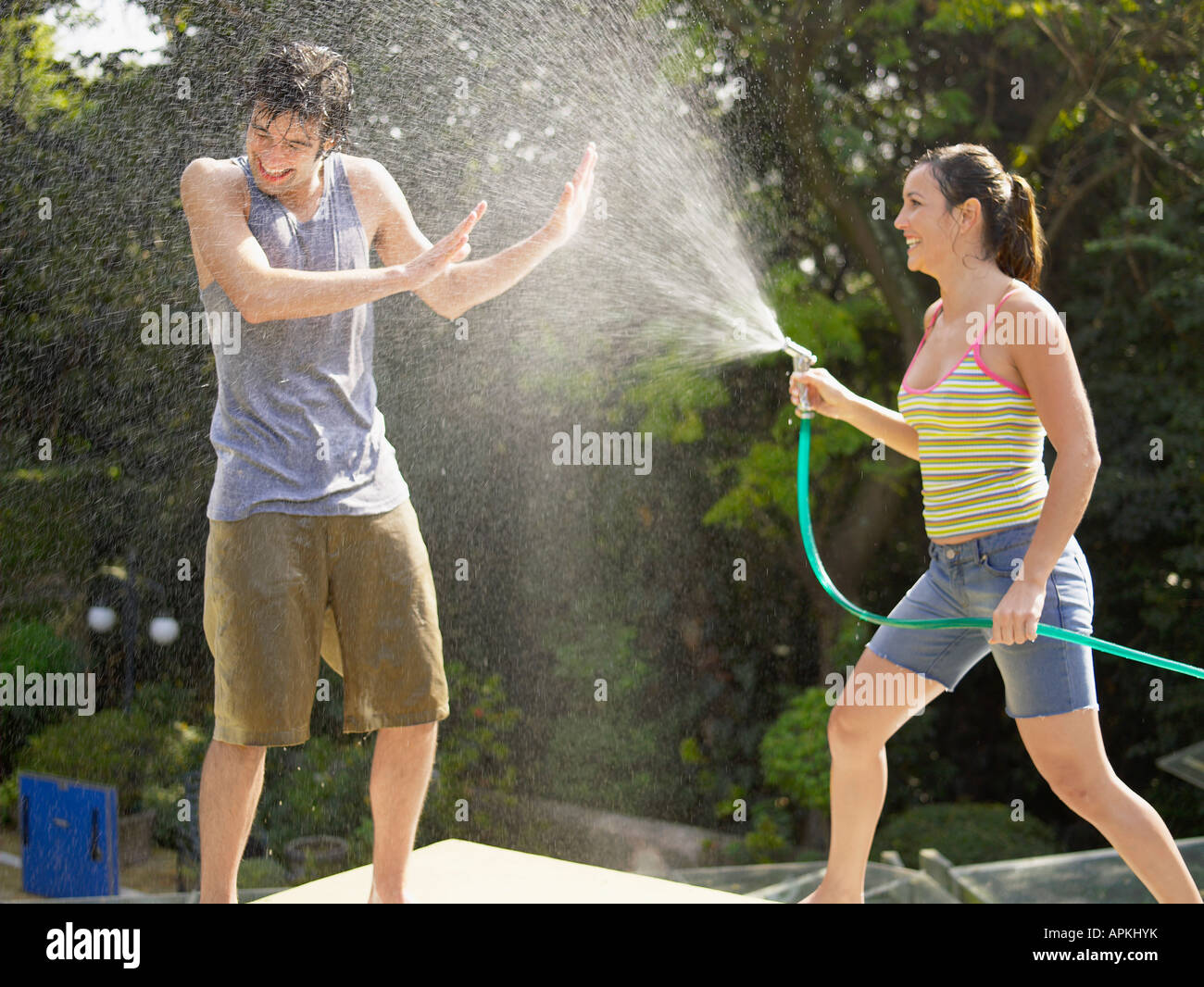 Young couple playing with water hose Stock Photo