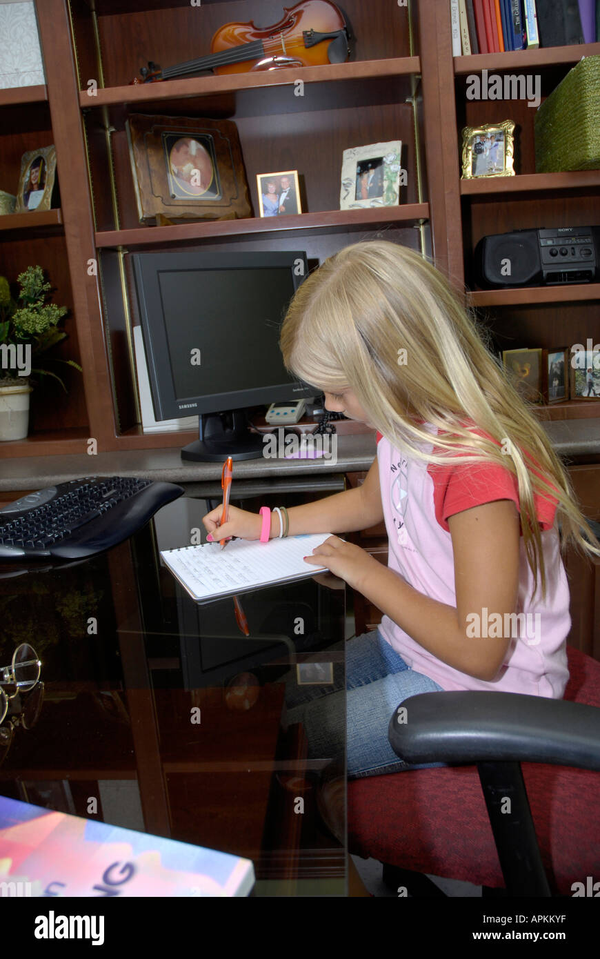 8 year old girl writes in her journal in the family office or den 