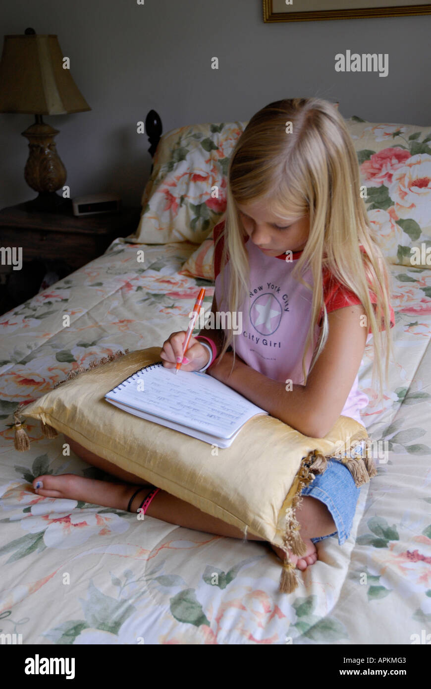 8 year old girl writes in her journal in her bedroom while laying 