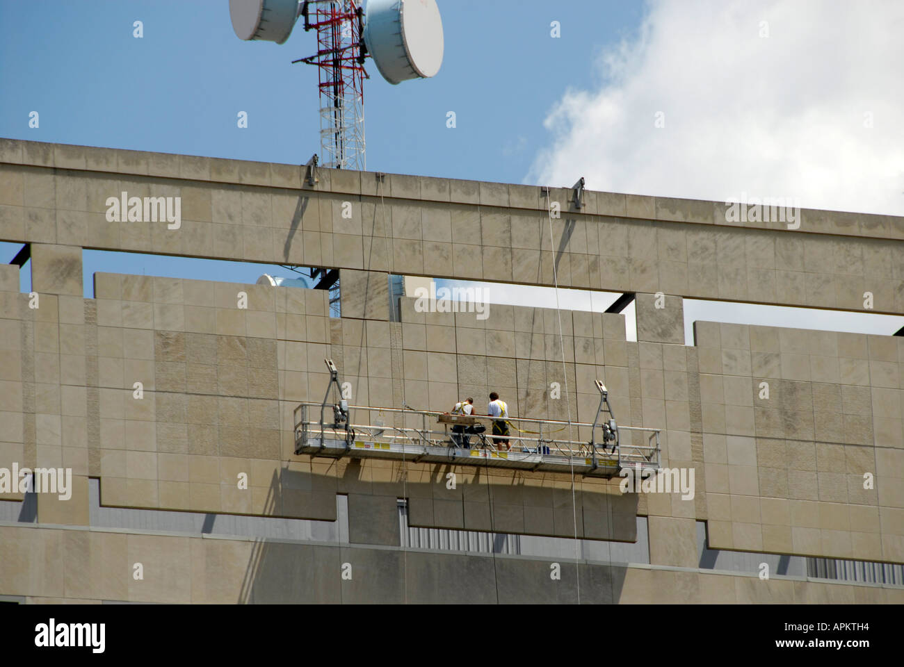Workman on the side of a building doing repairs on scaffold is a