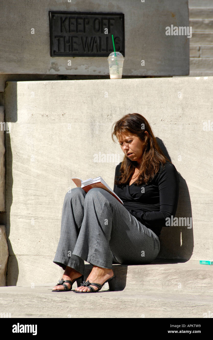 Female sitting reads book during lunch hour break in downtown