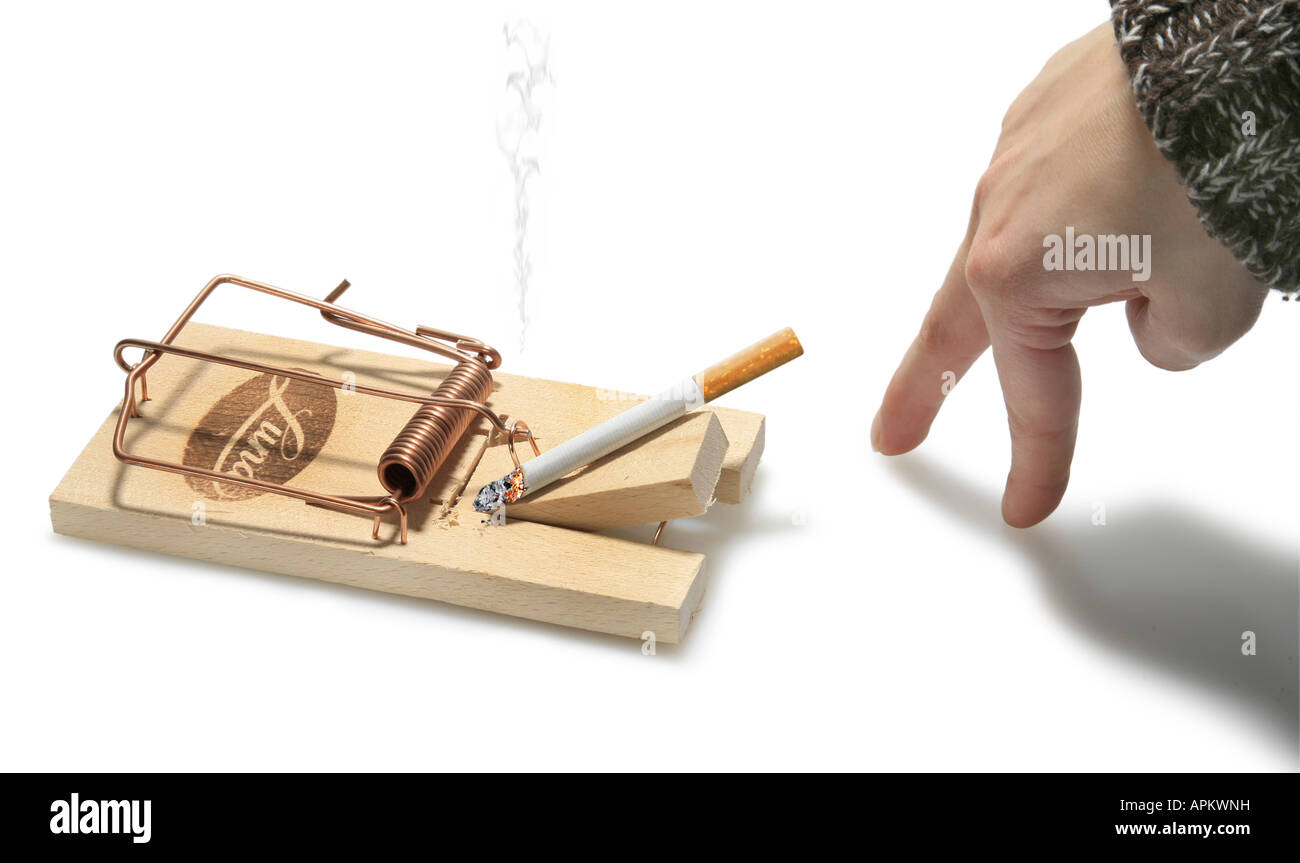 female fingers sneaking up a cigarette in a mousetrap Stock Photo