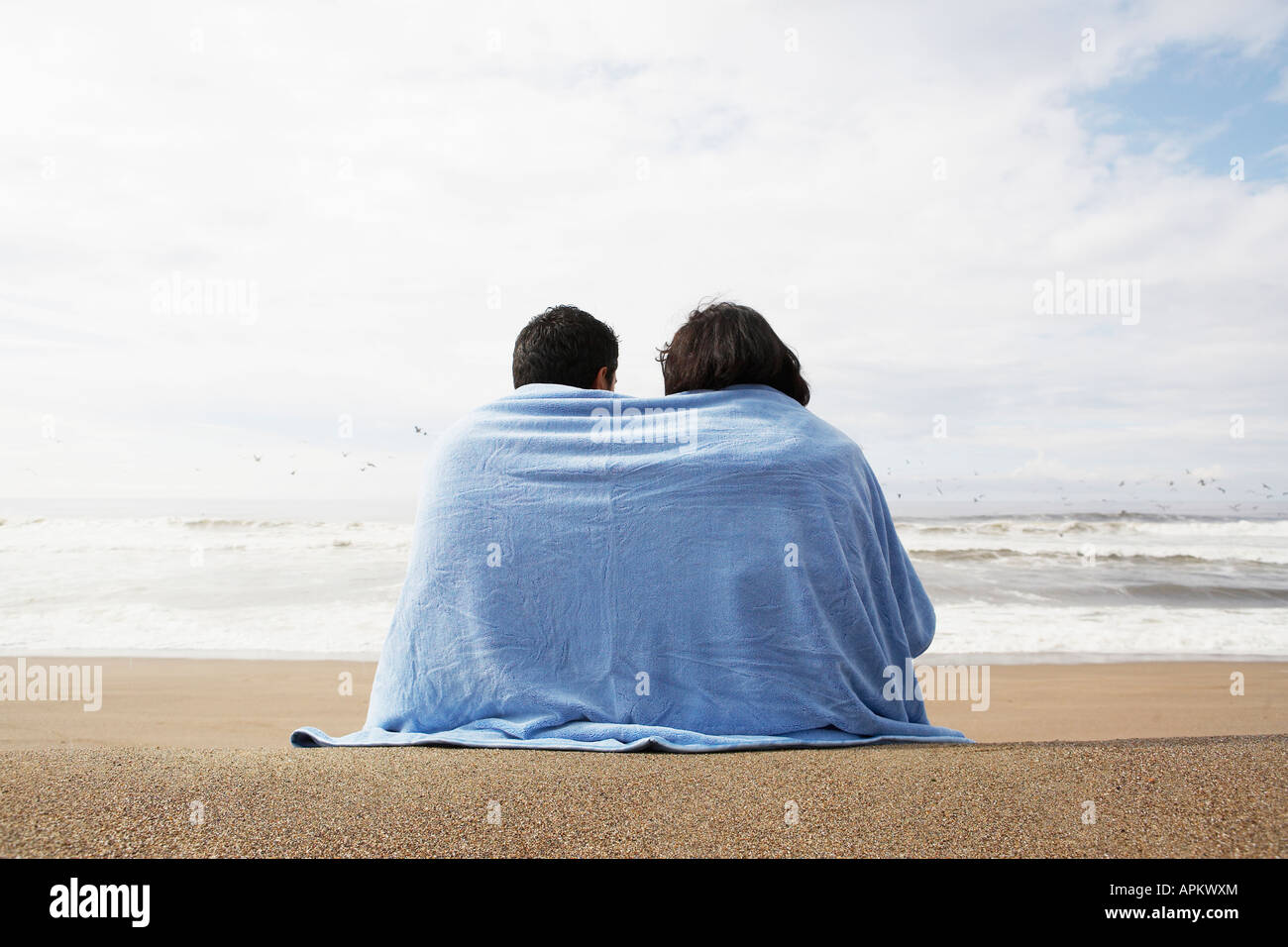 Young couple wrapped in towel on beach (rear view) Stock Photo