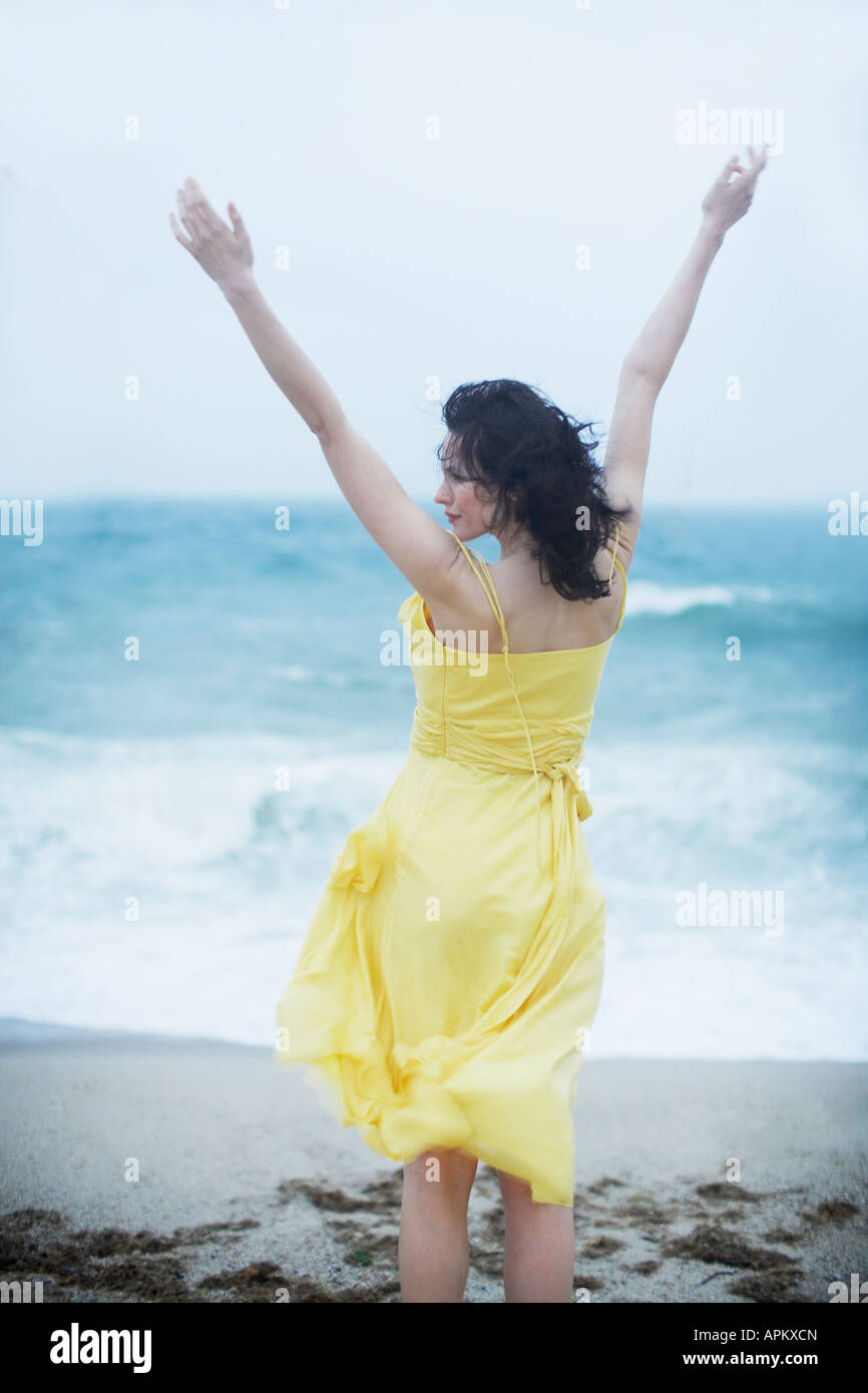 Young woman raising hands on beach Stock Photo - Alamy