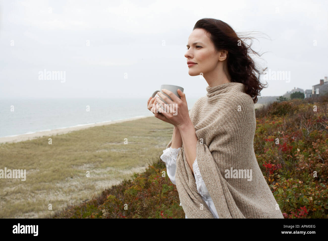 Young woman drinking coffee at beach Stock Photo - Alamy