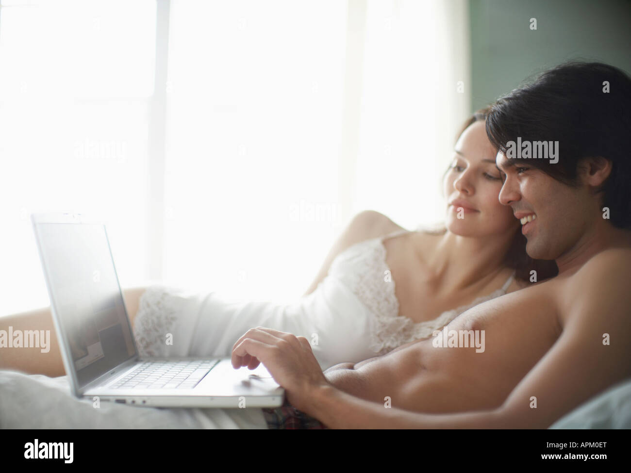 Young couple using laptop computer on bed Stock Photo