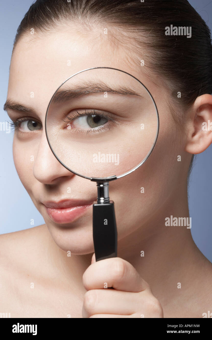 Young woman looking through magnifying glass Stock Photo - Alamy