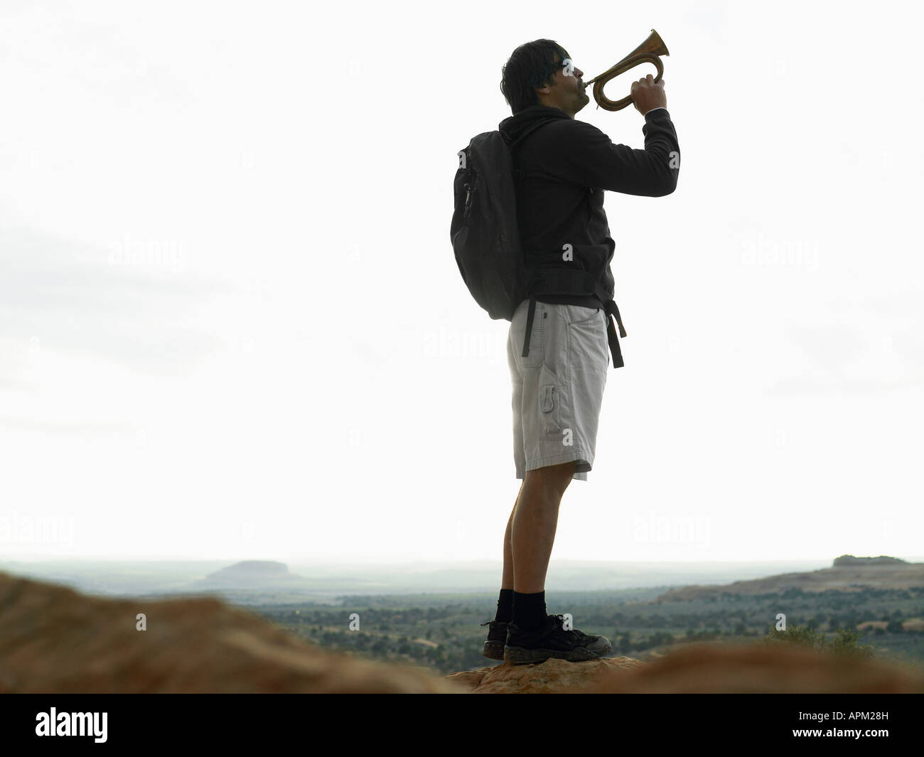 Mid adult man playing bugle on rock Stock Photo - Alamy
