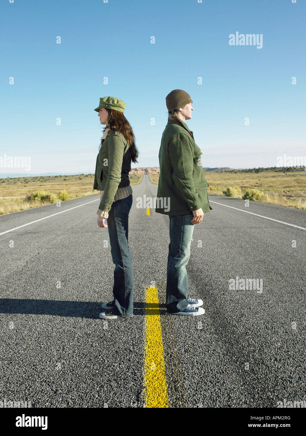 Woman and man standing back to back on highway Stock Photo
