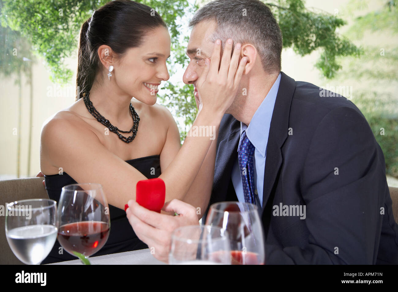 Woman touching man's face, man holding gift Stock Photo