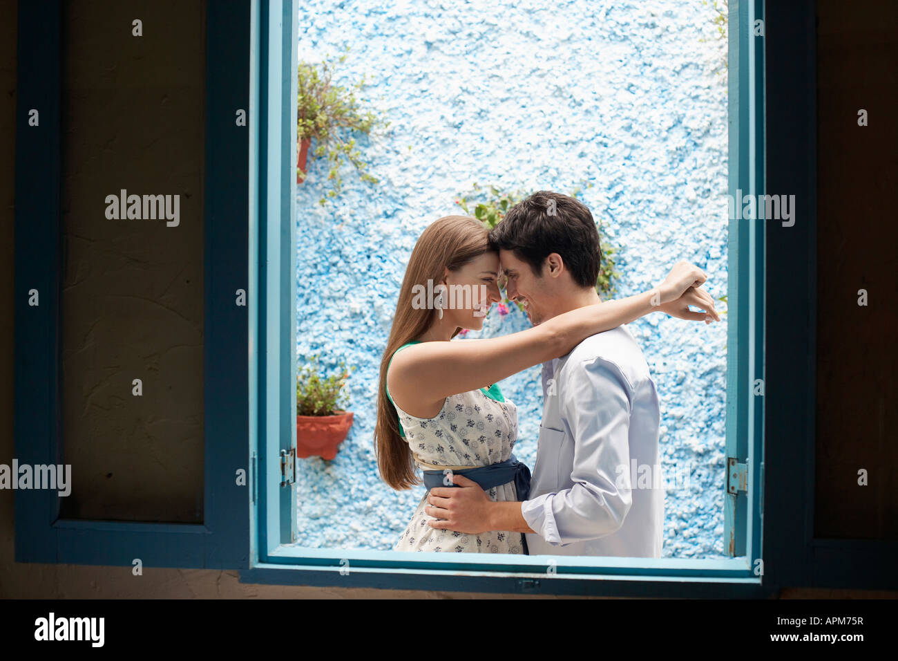 Couple hugging by window Stock Photo - Alamy