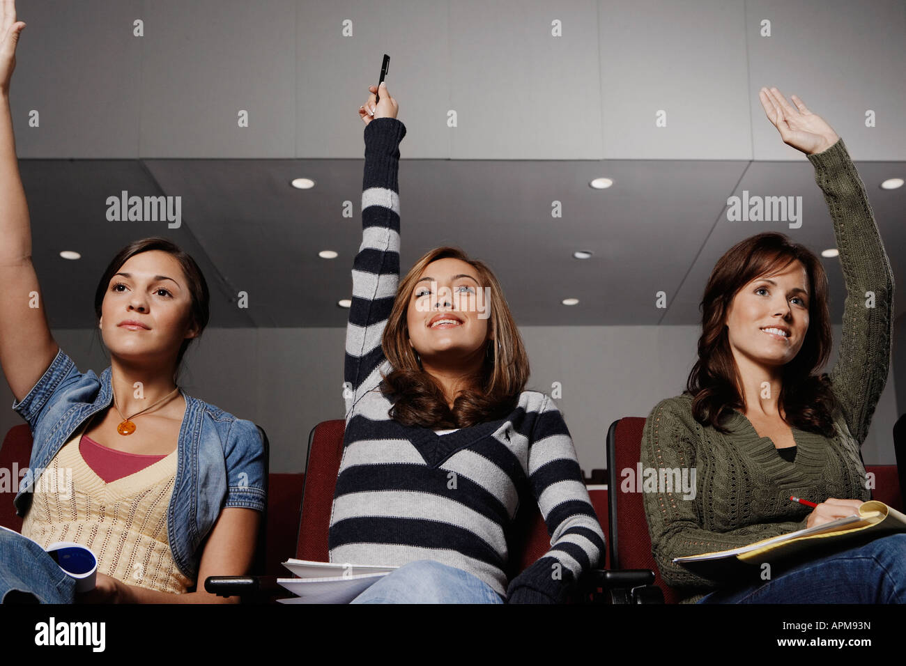 Three female students with raised arms Stock Photo - Alamy