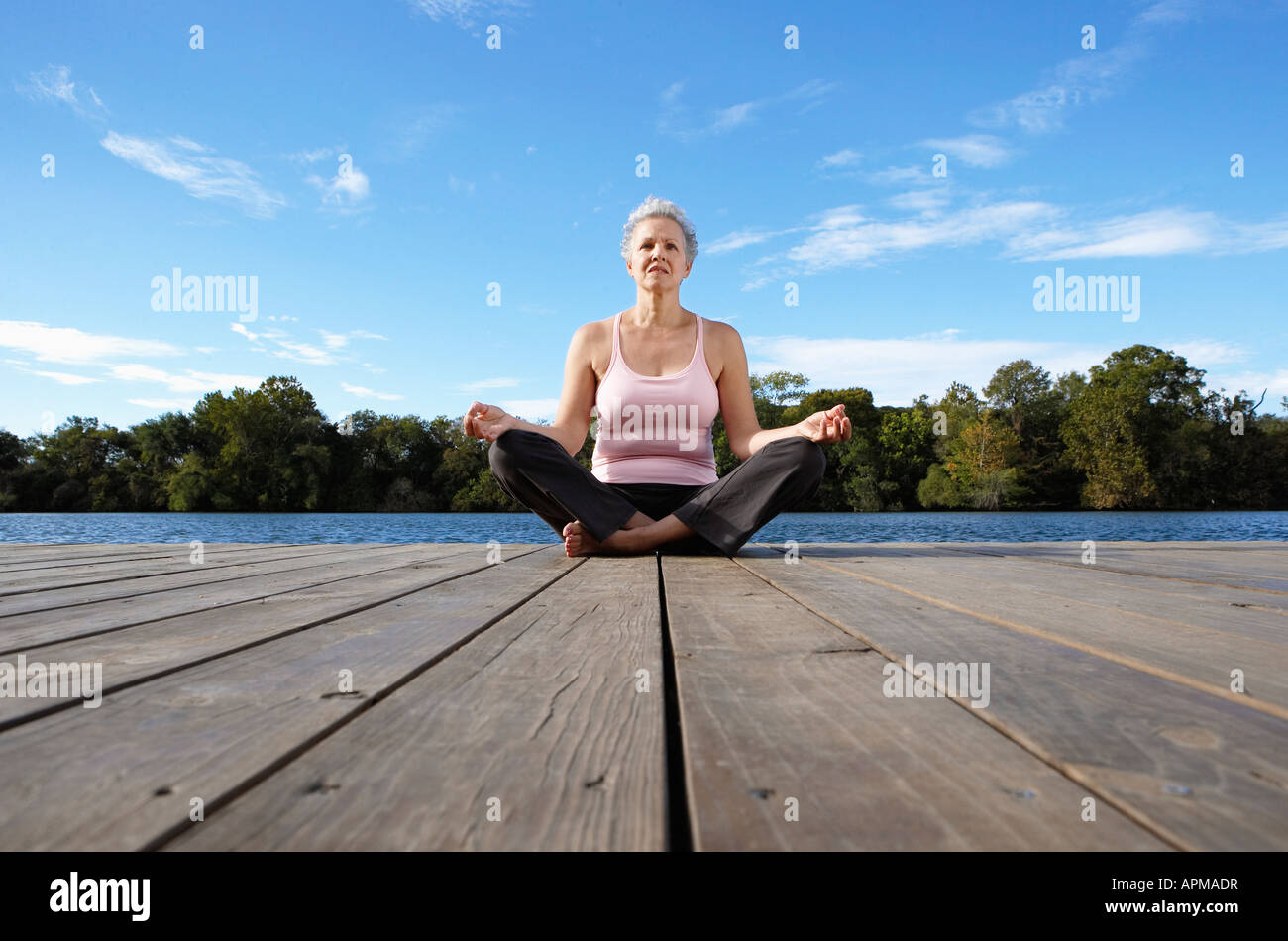 Mature woman meditating in lotus position (low angle view) Stock Photo